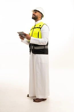 مهندس سعودي بالثوب التقليدي ومعدات السلامة مع جهاز لوحي