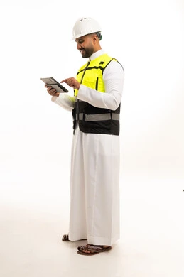 مهندس سعودي يرتدي سترة السلامة ويستخدم جهازاً لوحياً