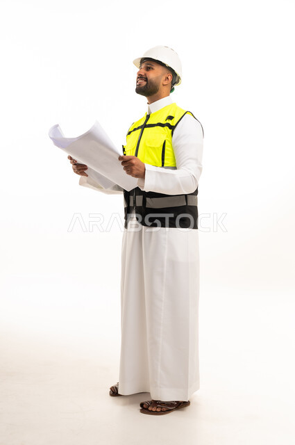 مهندس سعودي يرتدي سترة السلامة ويحمل مخططات هندسية