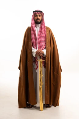 رجل سعودي بالبشت التقليدي يحمل سيفاً مذهباً