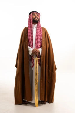رجل سعودي بالبشت التقليدي يحمل سيفاً ذهبياً