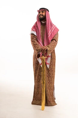 رجل سعودي باللباس التقليدي يحمل سيفاً مذهباً
