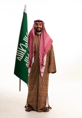 رجل سعودي بالزي الشتوي التقليدي مع العلم الوطني