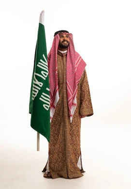 رجل سعودي مع العلم بالزي التقليدي والبشت