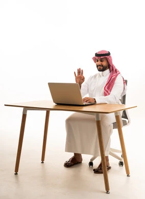 رجل سعودي بالزي التقليدي يستخدم اللابتوب في المكتب