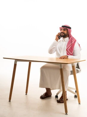 Saudi Businessman Sitting at Desk Talking on Mobile Phone