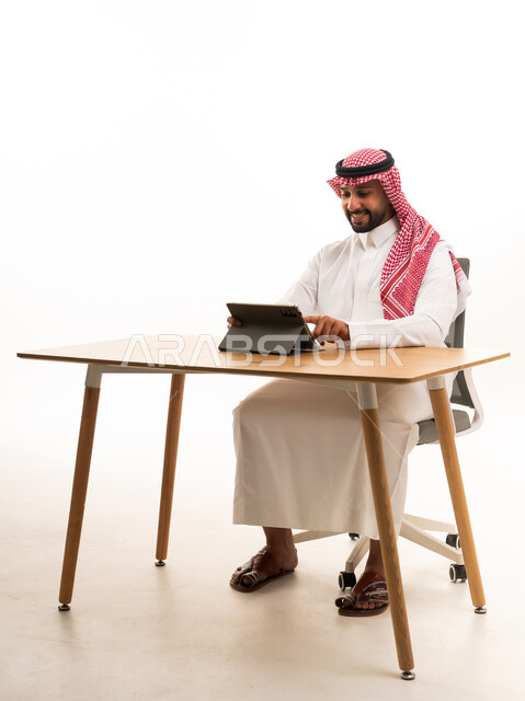 رجل سعودي يستخدم جهازاً لوحياً في المكتب
