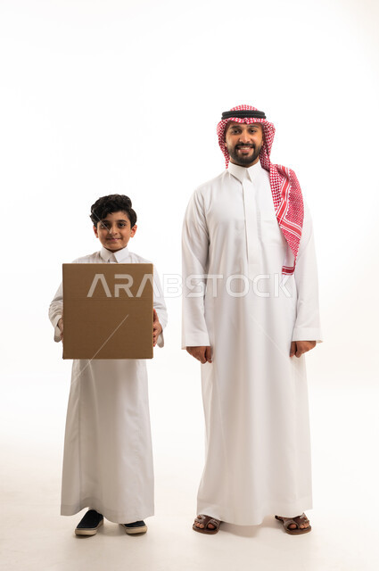 رجل وطفل سعودي يحملان صندوق كرتوني للتوصيل
