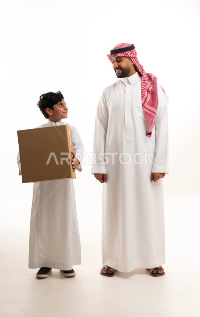 رجل سعودي وطفل مع صندوق كرتوني في الاستوديو