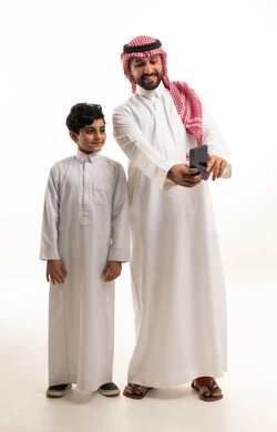 رجل سعودي وابنه يستخدمان هاتف ذكي خلفية بيضاء