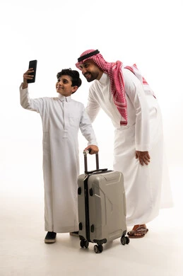 Saudi Man and Boy with Travel Suitcase Taking Phone Selfie