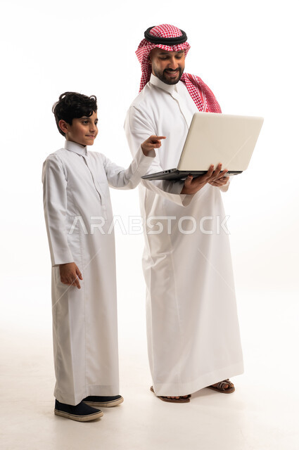 أب سعودي وابنه يستخدمان الحاسوب المحمول بخلفية بيضاء