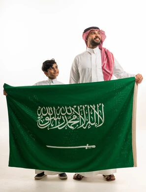 رجل وطفل سعوديان يحملان علم المملكة العربية السعودية