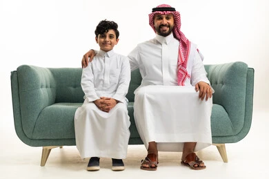 رجل وطفل سعوديان يجلسان بالزي التقليدي