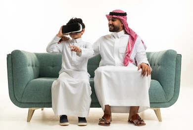 Saudi Father and Son Using VR Headset on Sofa