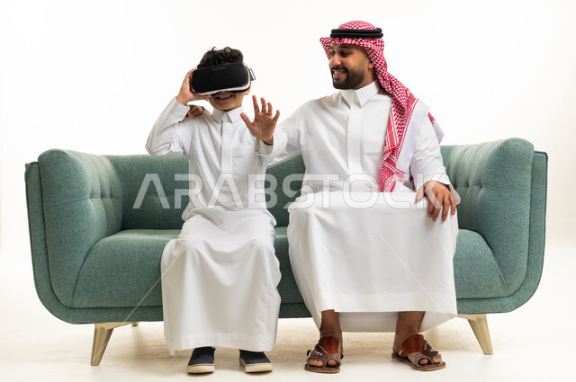 أب وابن سعوديان مع نظارة واقع افتراضي على الأريكة