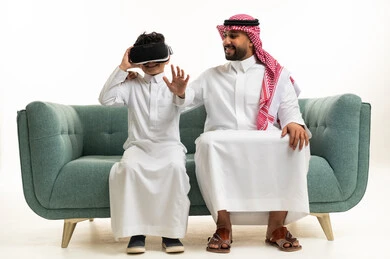 Saudi Father and Son with VR Headset on Green Sofa
