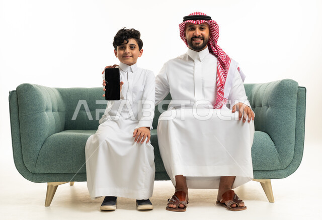 رجل سعودي وطفل مع هاتف ذكي على الأريكة