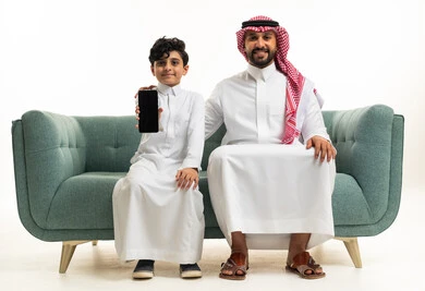Saudi Father and Son with Smartphone on Sofa