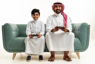 أب وابن سعوديان يلعبان ألعاب الفيديو معاً على الأريكة