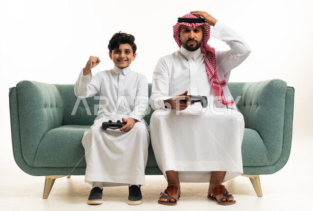 أب وابنه سعوديان يلعبان ألعاب الفيديو على الأريكة