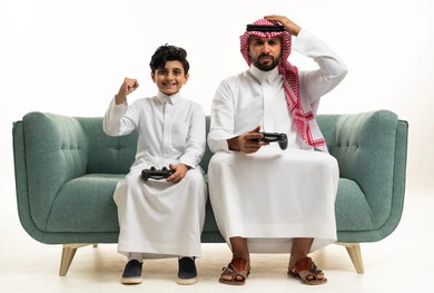 أب وابنه سعوديان يلعبان ألعاب الفيديو على الأريكة