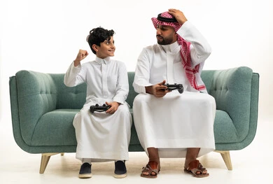 Saudi Father and Son Playing Video Games on Sofa