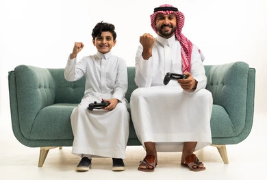 أب سعودي وابنه يلعبان ألعاب الفيديو على الأريكة