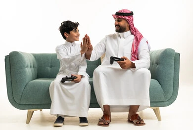 أب سعودي وابنه يلعبان ألعاب الفيديو على الأريكة