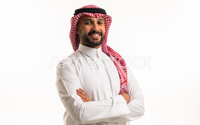 رجل سعودي مبتسم يرتدي الثوب والشماغ التقليدي بوضعية واثقة