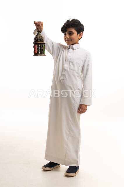 طفل سعودي بالثوب التقليدي يحمل فانوس رمضان