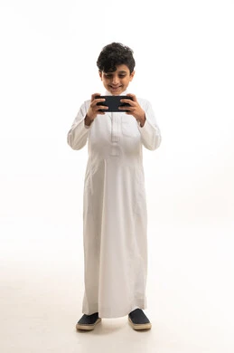 Saudi Boy in Traditional Thobe Using Smartphone Studio