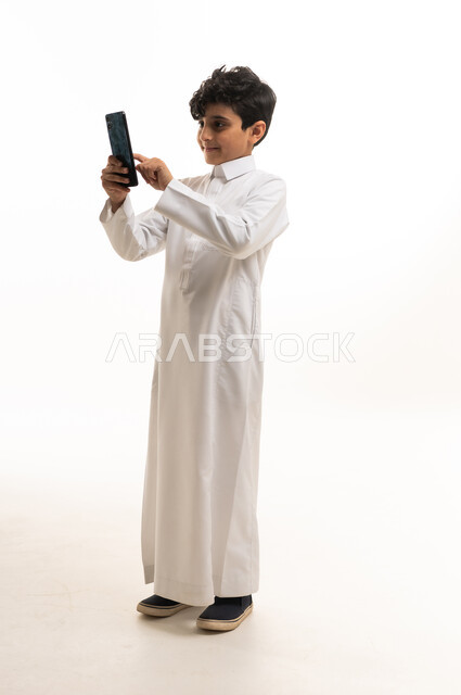 Saudi Boy in Thobe Using Smartphone on White Background