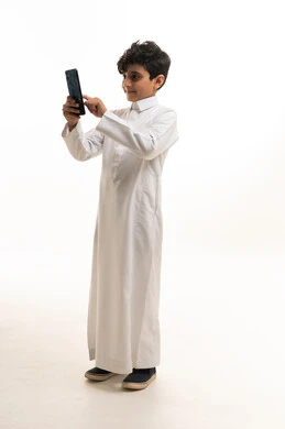 Saudi Boy in Thobe Using Smartphone on White Background