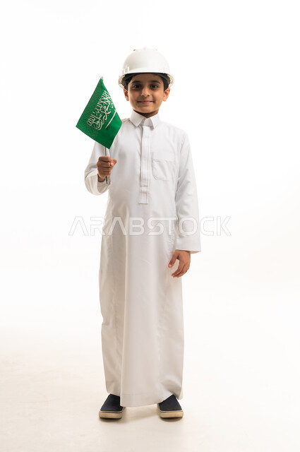 طفل سعودي بالثوب والخوذة يحمل العلم السعودي