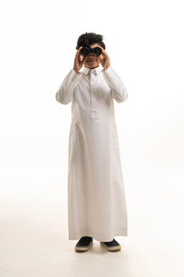 طفل سعودي بالثوب التقليدي يستخدم المنظار المكبر