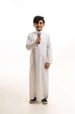 طفل سعودي بالثوب الأبيض يمسك ميكروفون في استوديو