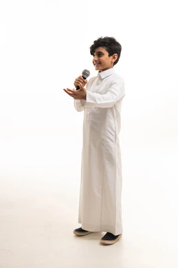 طفل سعودي بالثوب الأبيض يمسك ميكروفون