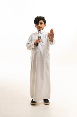 طفل سعودي بالثوب التقليدي يمسك ميكروفون ويشير بالتوقف
