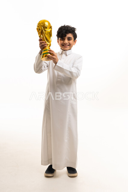 طفل سعودي بالثوب يحمل مجسم كأس العالم الذهبي