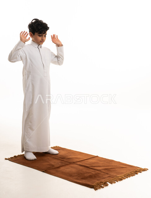 Saudi Boy in White Thobe Praying on Mat White Background