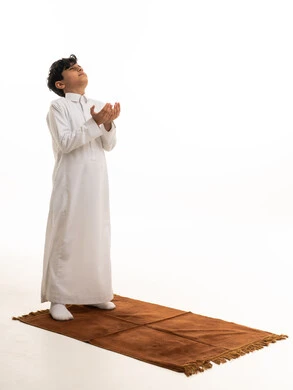 Saudi Boy in White Thobe Praying on Rug Studio Shot