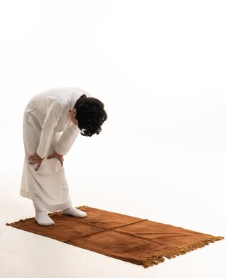 Saudi Boy Performing Ruku Prayer on Brown Mat