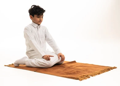 Saudi Boy in White Thobe Performing Prayer on Mat