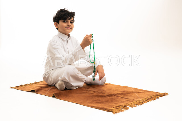 طفل سعودي بالثوب الأبيض مع مسبحة صلاة