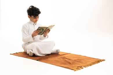 طفل سعودي يقرأ القرآن الكريم على سجادة صلاة