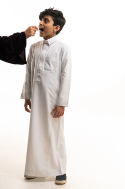 طفل سعودي بالثوب الأبيض يتناول الدواء السائل