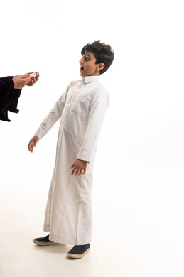 طفل سعودي بالثوب التقليدي بتعابير مندهشة خلفية بيضاء