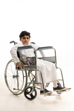 Saudi Boy in Wheelchair Wearing Traditional White Thobe