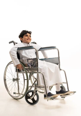 طفل سعودي بالثوب التقليدي يجلس على كرسي متحرك